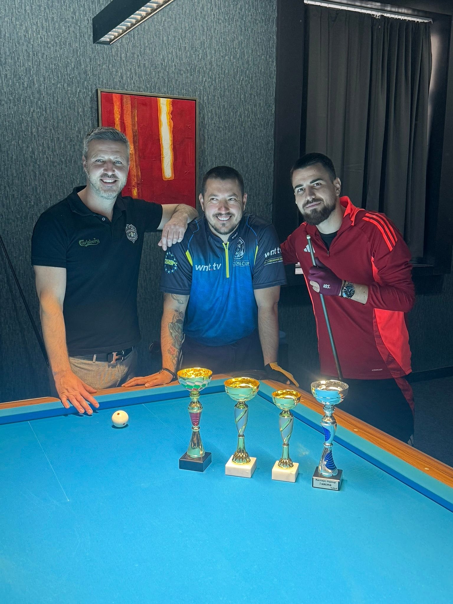 Three players with their trophies at the table